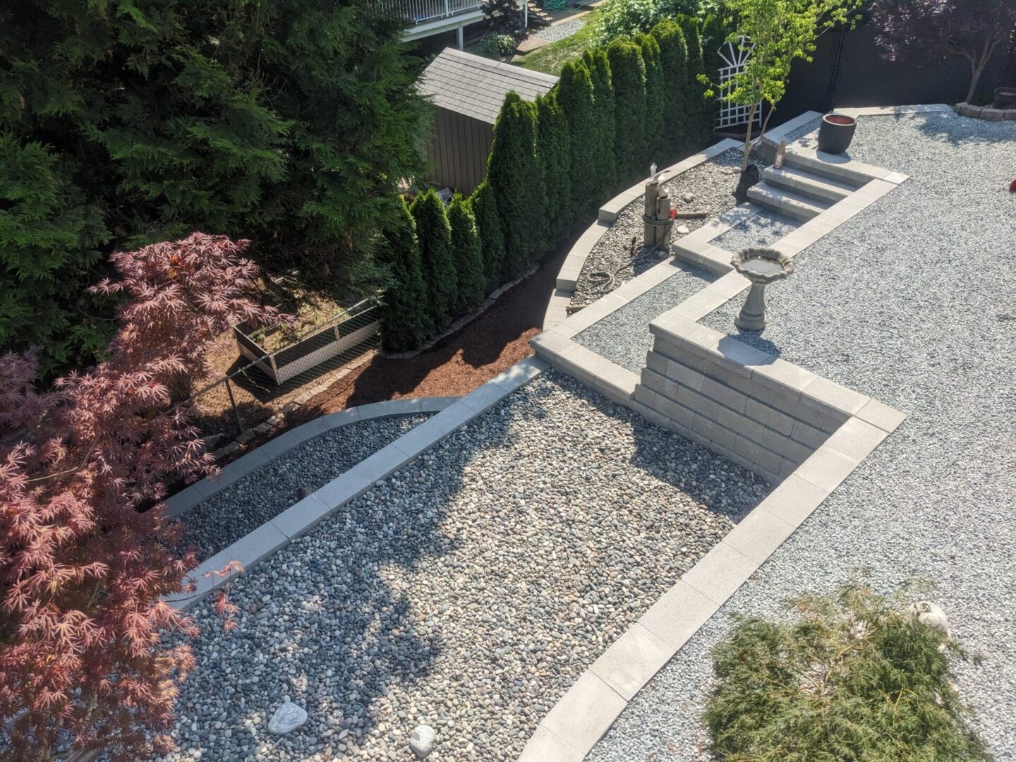 Aerial view of a landscaped garden with gravel paths, benches, and ornamental trees.